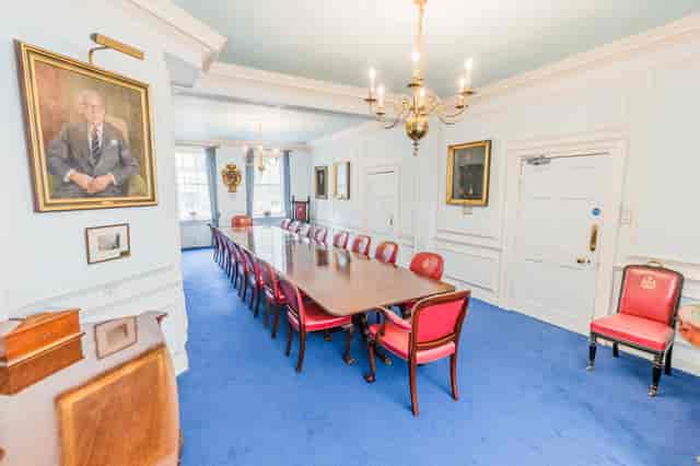 Elegant meeting room with wooden table and red chairs at Coopers' Hall for formal events.