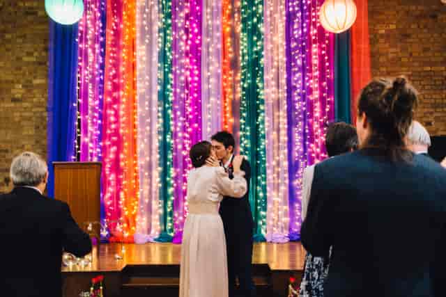 Vibrant wedding backdrop with lights in Unity Islington's Large Hall.