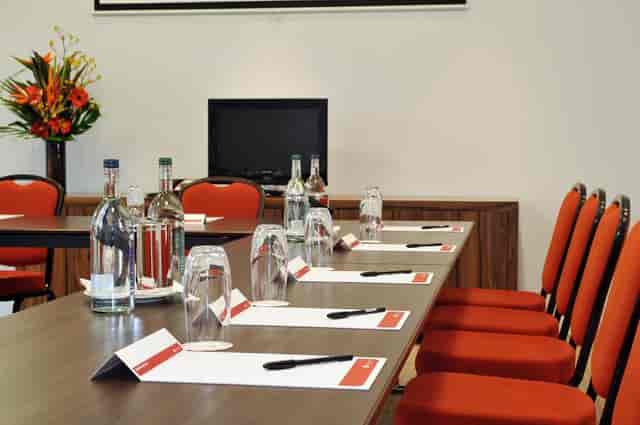 Supernova Suite meeting room with polished table, vibrant chairs for corporate events.