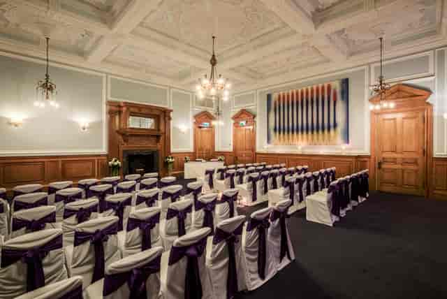 Elegant meeting space at Andaz London with white chairs and purple sashes for events.