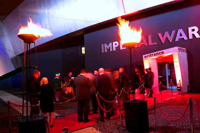 "Quayside entrance at Imperial War Museum North with red carpet and flame torches for upscale events."