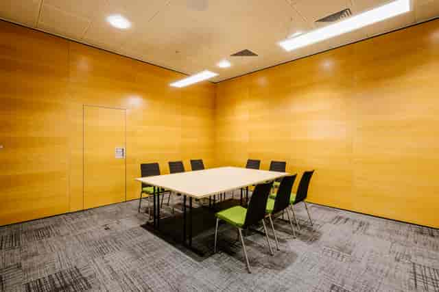 Modern minimalist meeting room in BMA House with warm wooden walls for collaboration.