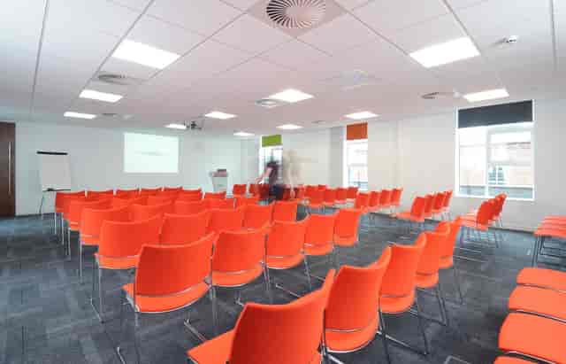 Modern meeting space with orange chairs, perfect for workshops and presentations.
