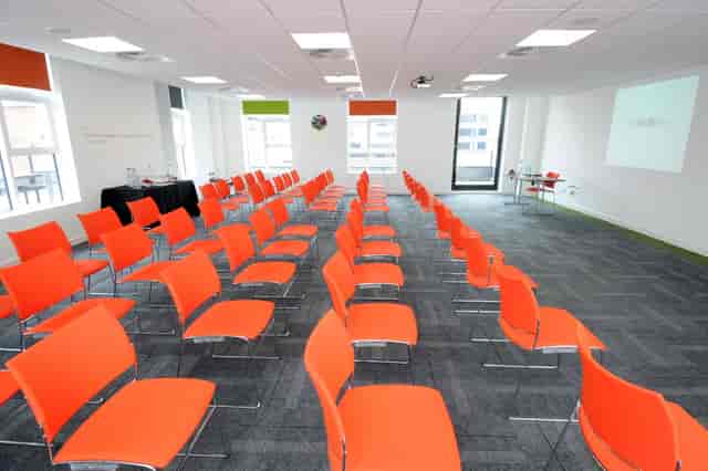 Modern meeting space with orange chairs for events, ideal for presentations and workshops.