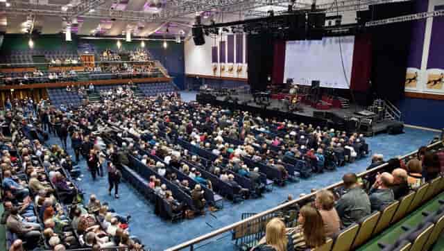 Centaur auditorium at Cheltenham Racecourse, filled audience for a live event.