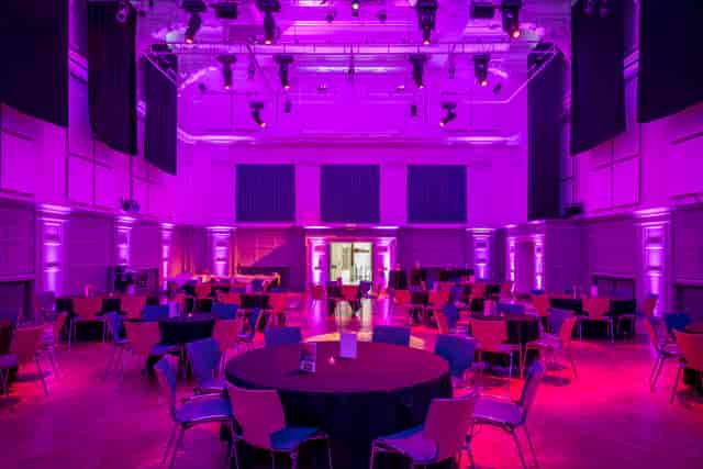 Great Hall at Bishopsgate Institute with round tables and vibrant purple lighting for events.