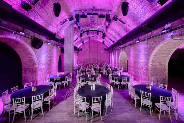 Stylish event space with round tables and purple lighting at The Steel Yard for corporate events.