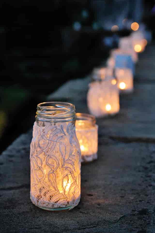 Illuminated lace jars centerpiece for outdoor evening events at Watts Gallery.