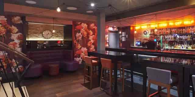 Modern bar area at Chez Mal, floral wallpaper, ideal for networking events and social gatherings.