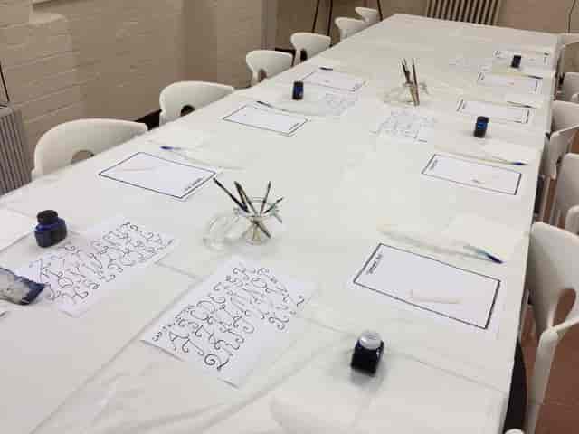Meeting room setup with long table for creative workshop and calligraphy session.
