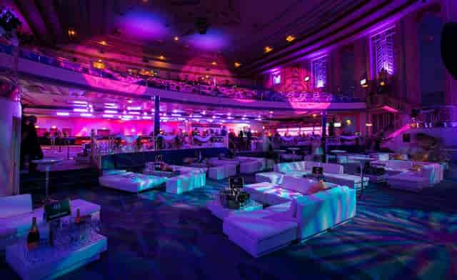 "Elegant Christmas party at Troxy with plush seating and vibrant purple lighting."