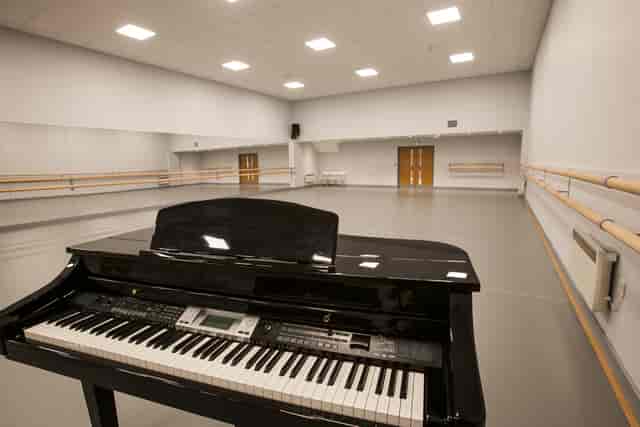 Spacious dance rehearsal studio with black piano, ideal for events and workshops.