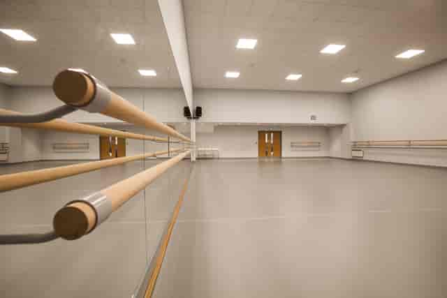 Spacious dance studio with mirrored wall and ballet barre for workshops and events.
