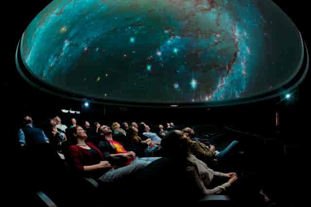Captivated audience in Peter Harrison Planetarium during an immersive cosmic event.