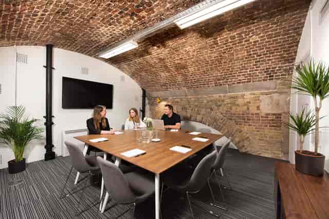 Modern meeting room with wooden table, exposed brick, ideal for events and discussions.