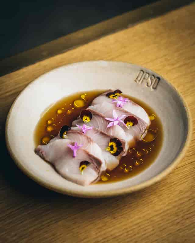 Elegant fish dish with edible flowers in OPSO's Main Dining Room for events.