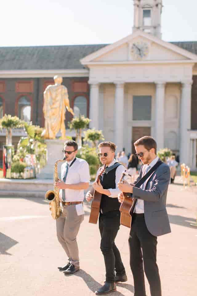 Lively outdoor event at Royal Hospital Chelsea with musicians playing saxophone and guitars.