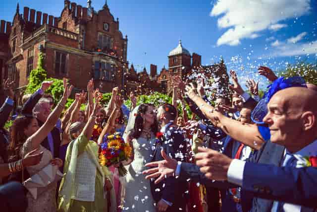 "Vibrant wedding celebration in Great Hall, Aston Hall with guests throwing confetti."