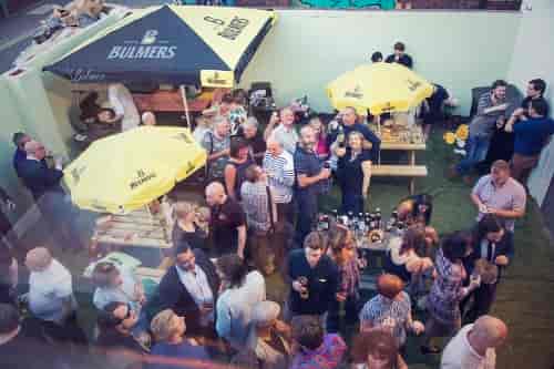 Vibrant outdoor networking event at The Night Owl with branded umbrellas and food stations.