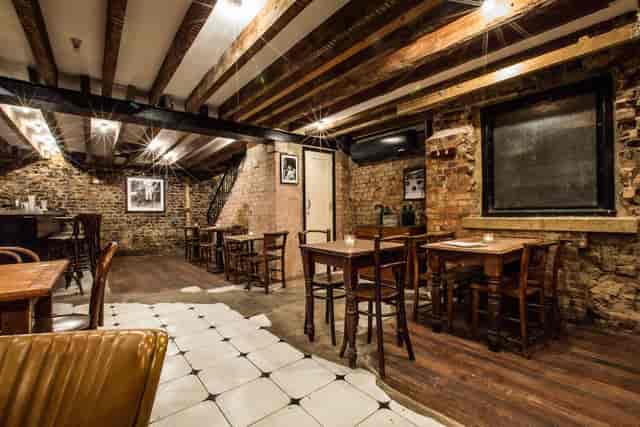 Rustic basement event space with exposed brick, ideal for gatherings and networking.