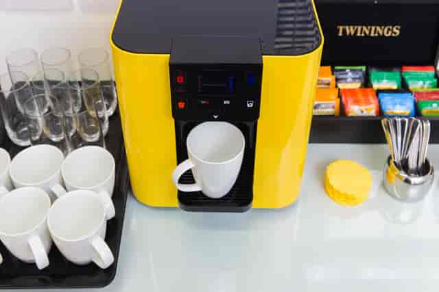 Vibrant coffee station with yellow machine in BakerStreetQ Meeting Space for events.