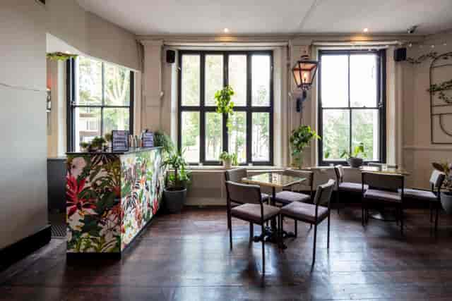Stylish event space with large windows and floral bar, ideal for meetings and gatherings.