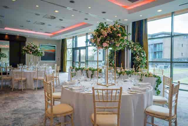 Garden Suite banquet room with gold chairs and floral centerpieces for weddings and events