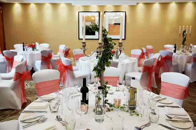 Elegant wedding event space at Charles and James Suites, adorned with pink sashes and candles.