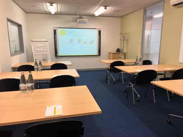 Picasso workshop setup with tables, notepads, and projector in a bright meeting room.