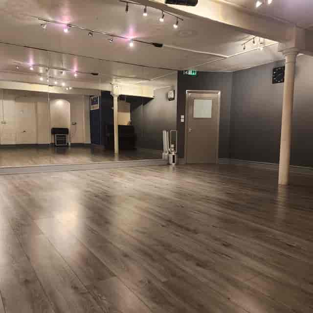Versatile recording studio with polished wooden floor, ideal for workshops and fitness classes.