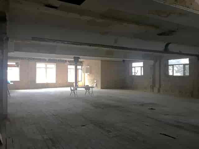 Spacious unfinished event space with large windows for corporate meetings and social events.