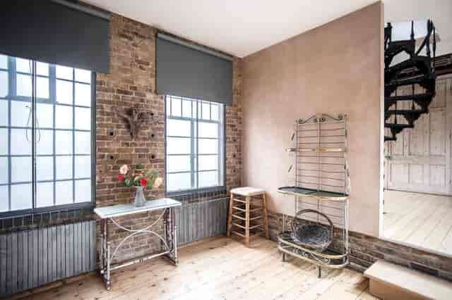 Versatile event space with exposed brick and spiral staircase for meetings and workshops.