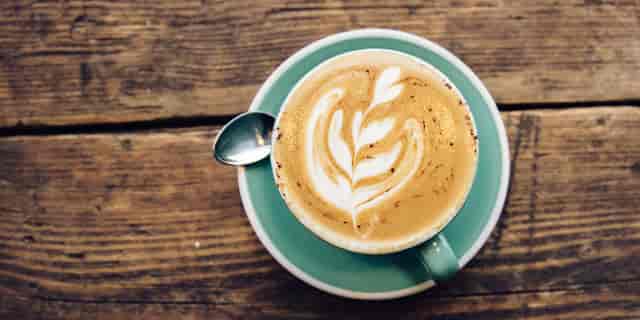 Intricate latte art in stylish cup on rustic table, perfect for networking events.