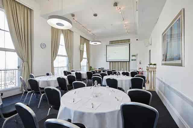 Well-lit meeting room with round tables, ideal for conferences and workshops.