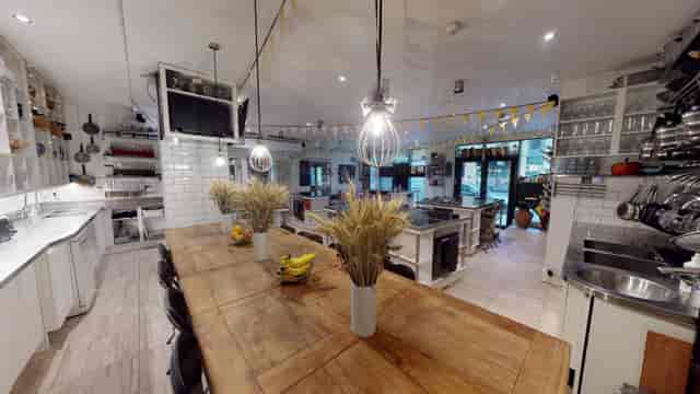 Spacious professional kitchen for rent with large wooden table, ideal for cooking classes.