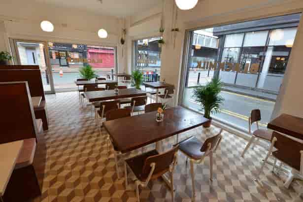 Bright Black Milk Cafe with wooden tables, perfect for casual meetings and events.
