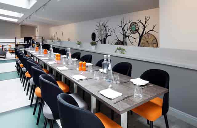 Modern meeting space at Wesley Euston Hotel, featuring vibrant black and orange chairs.