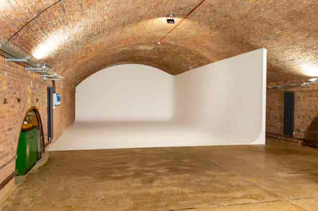 Versatile event space in Rida Haggerston with exposed brick and curved white wall.