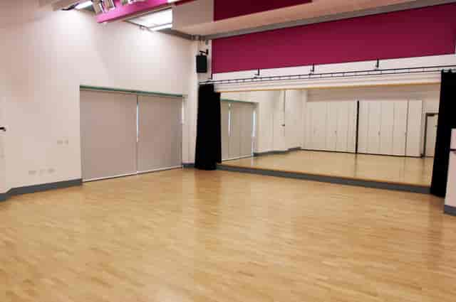Dance studio with polished wooden floor and mirrors, perfect for workshops and fitness classes.