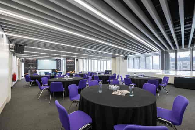 Modern event space at QEII Centre with round tables and vibrant purple chairs.