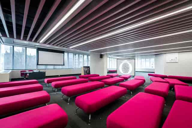 Olivier in vibrant pink seating at QEII Centre, ideal for workshops and presentations.