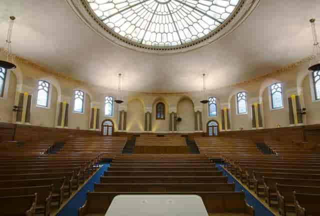 Historic Emmanuel Centre auditorium with tiered wooden seating for academic seminars and town halls.
