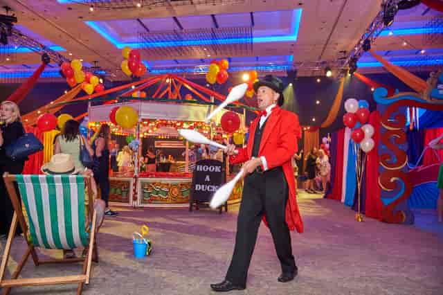 Carnival-themed event at Bankside Ballroom with juggler and colorful decorations.