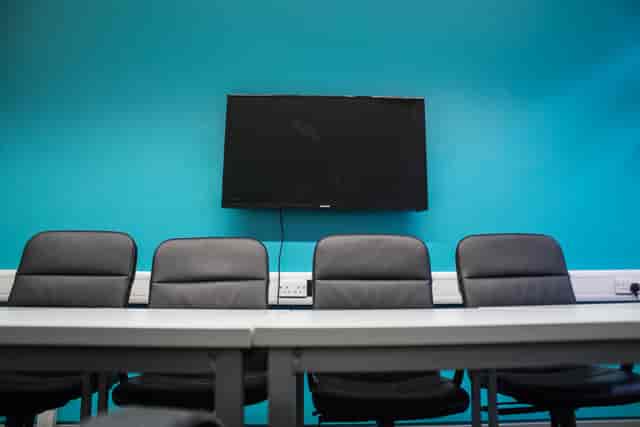 Modern meeting room with sleek black chairs and large screen for presentations.