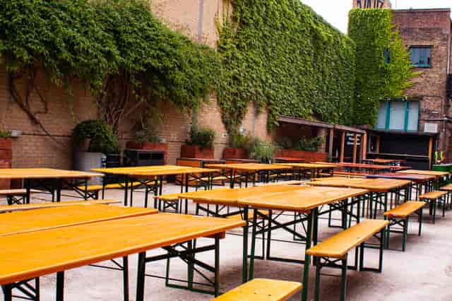 Outdoor event space with wooden tables in Strongroom Bar & Kitchen for casual gatherings.