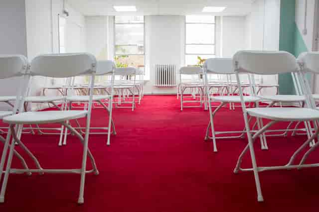 Events Space in Space4 with white chairs on red carpet, perfect for workshops and seminars.