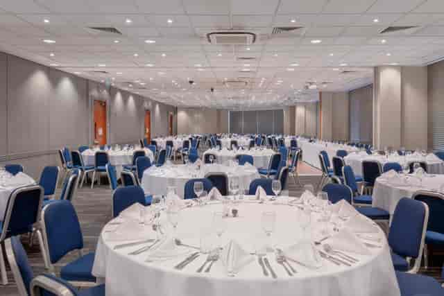 Banquet hall at Holiday Inn Kensington, set for events with elegant decor and blue chairs.