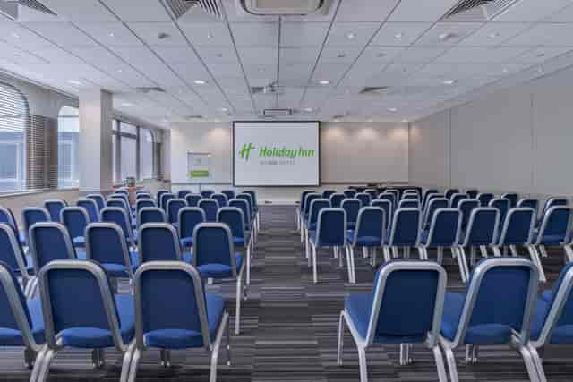 Conference room with blue chairs at Holiday Inn London Kensington Forum for events.