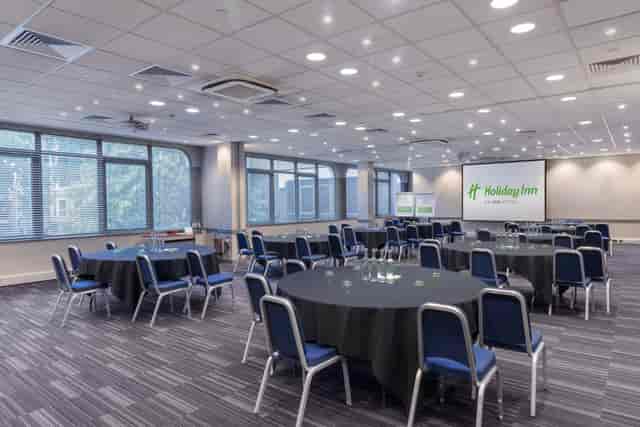 Versatile meeting space with round tables at Holiday Inn London Kensington for corporate events.