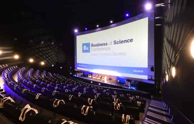 Modern auditorium with tiered seating for Business of Science Conference networking event.